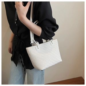 Detailed close-up of white woven texture and elegant knot detail on stylish tote bag