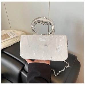 Detail of white marble shell clutch with artistic silver wavy handle and chain strap