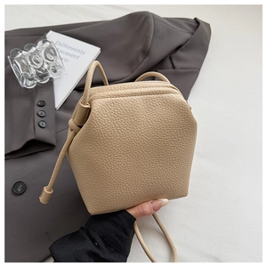 Detail of beige pebble leather bucket bag with drawstring and textured hexagonal design