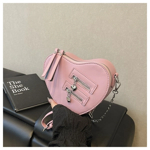 Detailed shot of a pink heart-shaped crossbody bag with silver chains and heart charms