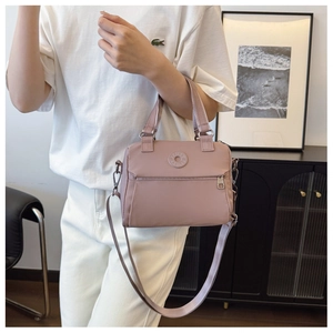 Detail of dusty pink nylon crossbody bag with circular logo and adjustable strap
