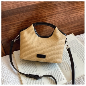 Détail du sac en paille tressée avec bordure en cuir noir et bandoulière réglable