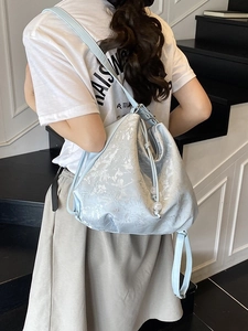 Light blue embroidered drawstring backpack with pearl charms shown on a model