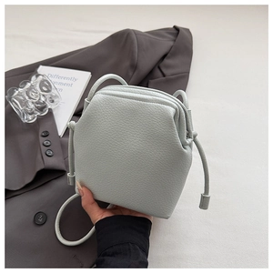 Detail of light green pebble grain leather bucket bag with elegant gathered texture and drawstring