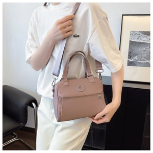 Detail of mauve nylon handbag with adjustable shoulder strap and woven dual handles