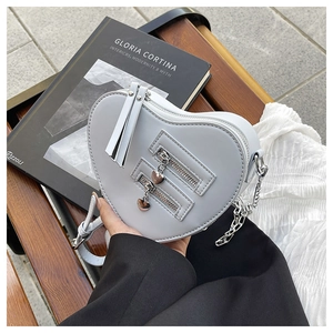 Detail of light blue heart-shaped crossbody bag with silver heart zipper pulls on wood