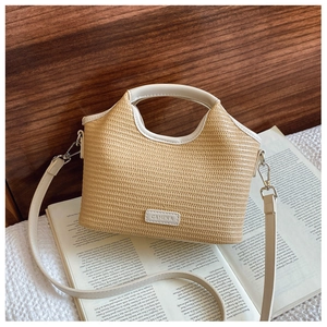 Détail d'un sac en paille avec bordure en cuir crème et logo sur fond de bois sombre