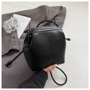 Close-up of a black lychee texture leather bucket bag with slim drawstring closure