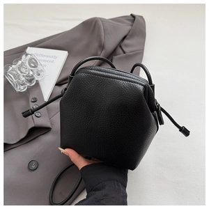 Detail of black lychee grain geometric handbag featuring drawstring and slim handle