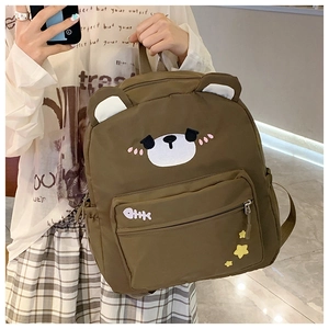 Detailed close-up of brown canvas bear backpack with cute embroidery and 3D ears