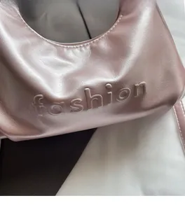 Close-up of premium pearlescent pink handbag featuring embossed fashion lettering detail