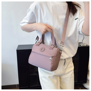 Detail of mauve nylon square bag showing sturdy handle and detachable wide shoulder strap