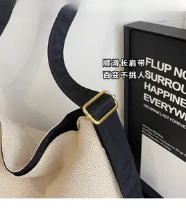 Detail of adjustable black wide shoulder strap with golden metal buckle on canvas tote bag