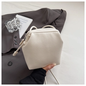 Detailed macro view of the cream mini crossbody bag showing lychee grain leather texture