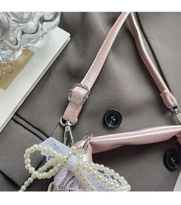 Detail view of pink metallic leather strap with silver buckle and pearl lace bow charm