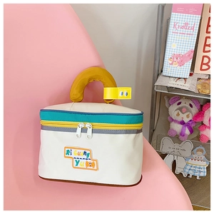 Detailed close-up of a house-shaped makeup bag with colorful zippers and a soft yellow handle