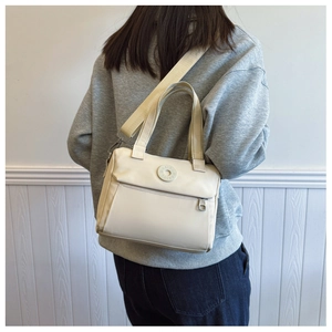 Detail of cream white nylon crossbody bag showing the woven strap and front pocket