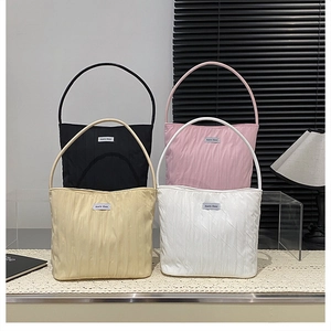 Detailed view of four colorful pleated nylon tote bags with brand label in lifestyle setting