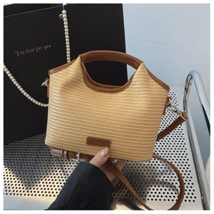 Détail du sac demi-lune tressé avec poignées en cuir marron et plaque de la marque