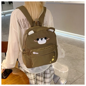 Close-up of cute brown bear backpack featuring 3D ears and detailed facial embroidery