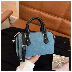Detail of a mini denim pillow bag with black leather trim and silver hardware details
