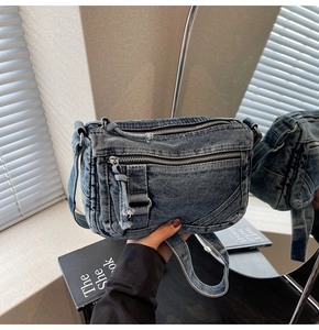 Detailed view of deep blue denim crossbody bag with multiple metal zipper pockets