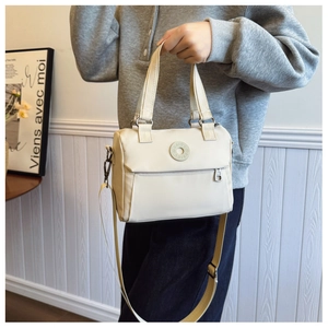 Detail of cream nylon crossbody bag featuring wide strap and front zipper pocket