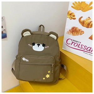 Detail of cute brown bear backpack with 3D ears and embroidered cartoon face on front pocket