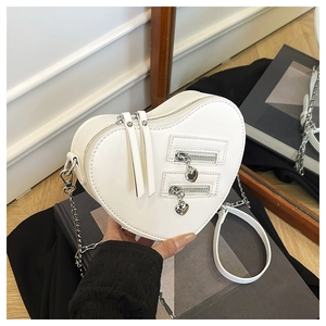 Detail of white heart-shaped leather crossbody bag featuring silver chain and dual zippers