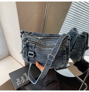 Detail of vintage blue denim crossbody bag featuring multiple zippers and silver hardware