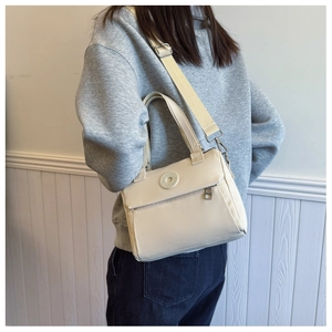 Detail of beige nylon crossbody bag with adjustable wide strap and circular front logo