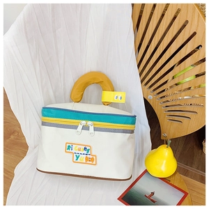 Detail of cute house-shaped cosmetic bag with colorful embroidery and yellow handle