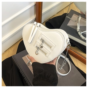 Detail view of white heart-shaped crossbody bag featuring silver chain and heart zipper charms