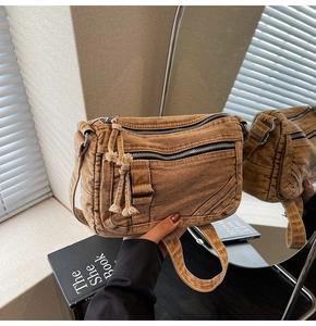 Detail of vintage brown denim crossbody bag showing washed texture and multi-zipper design