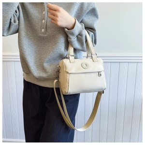 Cream white shoulder bag showing detachable strap and front zipper pocket detail