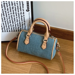 Detail of mini denim pillow bag with brown leather handles and silver hardware