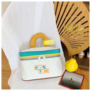 Detail of cute house-shaped makeup bag with yellow handle and cartoon decorative tag