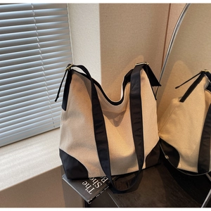 Macro detail of minimalist canvas tote bag with black reinforced corners and soft shoulder strap