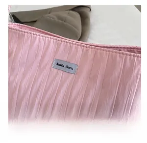Detail of pink pleated canvas bag fabric with brand label and fine silk-like texture