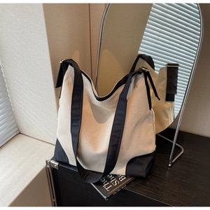 Detail of canvas tote bag with black strap and gold buckle near oval mirror