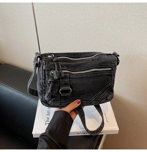 Close-up of vintage washed denim crossbody bag featuring multiple metal zipper pockets