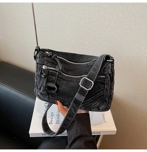 Detail of black denim crossbody bag featuring silver zippers and textured fabric