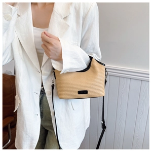 Vue détaillée du sac seau en paille tissée avec bordure en cuir noir et bandoulière