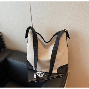 Detail view of cream canvas tote bag with black strap and metallic adjustment buckle