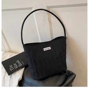 Detailed view of black quilted canvas shoulder bag featuring a circular leather handle