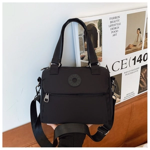 Detail of black nylon crossbody bag featuring round DAIOU logo and sturdy metal zippers
