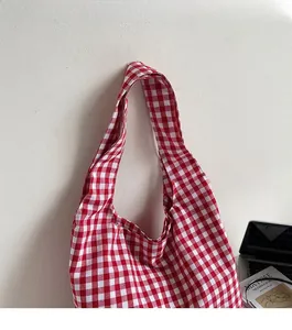 Close-up of comfortable wide strap on red gingham canvas tote bag with books