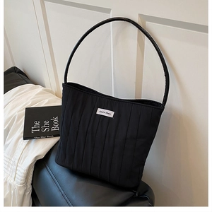 Detail of black quilted canvas bucket bag with Ann's then label and soft puff texture