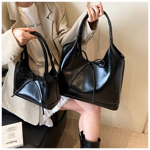 Detail of two black PU leather tote bags with large decorative bows for women
