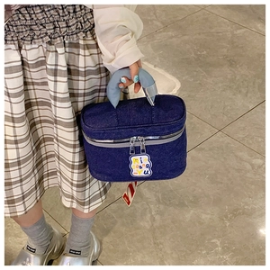 Macro shot of dark blue denim vanity bag with light blue handle and colorful embroidery